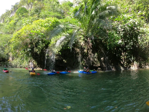 5 kayakers below natural waterfalls from jungle trees into the river Antioquia Colombia