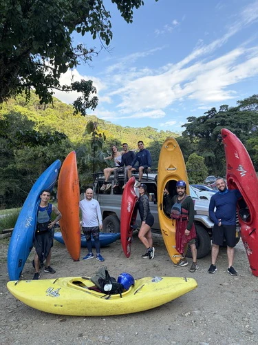 Group of 8 kayakers and their kayaks in front of the car