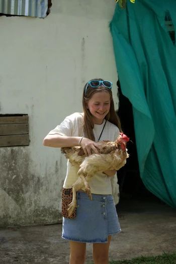 Girl holding a chicken and laughing