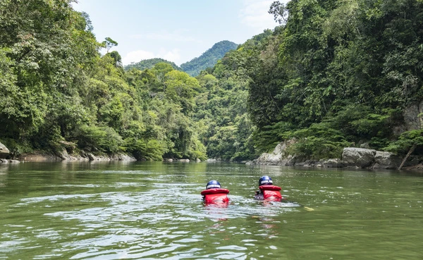 Two swimmers with red life-jackets in the rio verde, Colombia