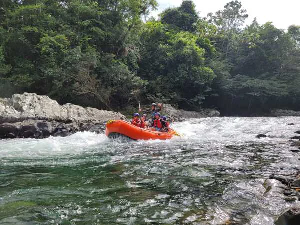 Group of happy clients celebrating with standing guide in the raft on the Santo Domingo River Colombia