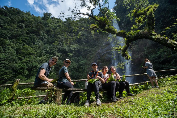 Group enjoying a traditional Colombian fiambre lunch in front of la esmeralda waterfall in the Waterfall Valley.