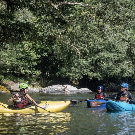 3 kayakers (1 woman, 2 men) in the introductory kayak course, learning paddle stroke techniques