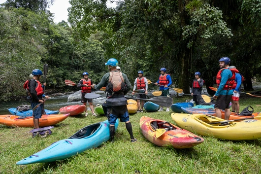 Kayak group class in a circle, all holding their paddle near their kayaks