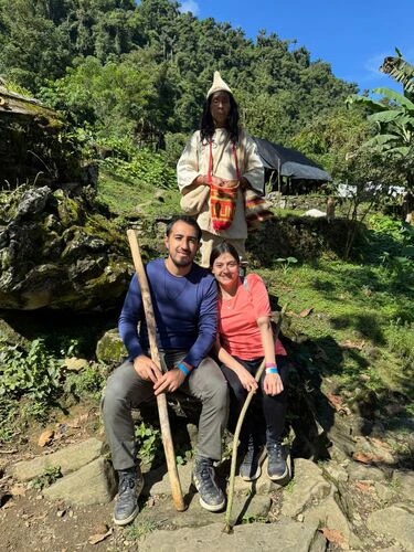 2 tourists posing with a kogui in front of their traditional homes in the lost city