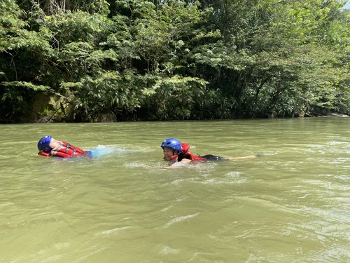 2 clients swimming in the river with their rafting equipment