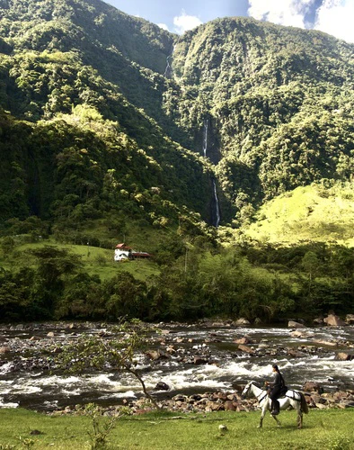 Woman horse riding in front of the Esmeralda Waterfall in the valley of the waterfalls.